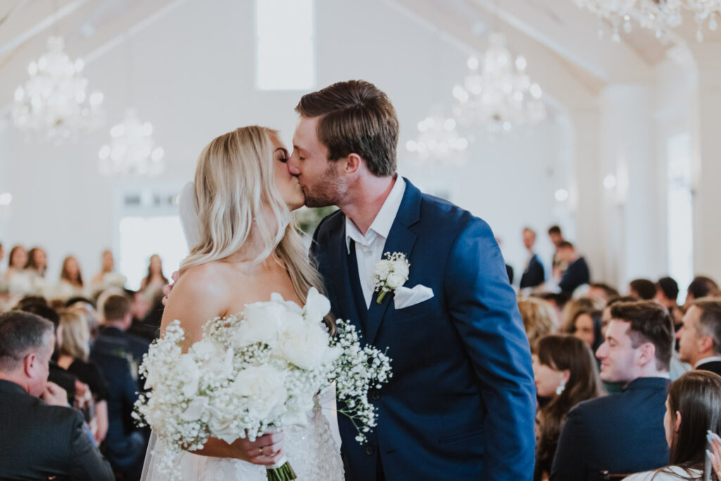 bride and groom kissing while walking down the aisle after their ceremony at the villa blanca space of the white room in st. augustine  