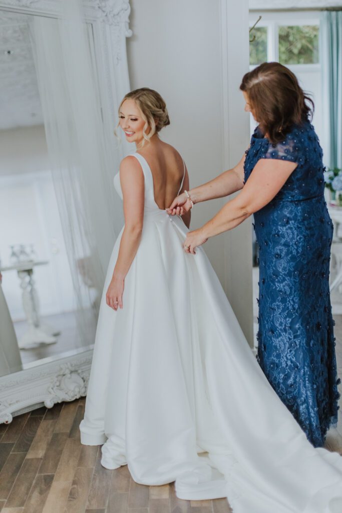 mother of bride zipping up the brides dress in the grand ballroom bridal suite