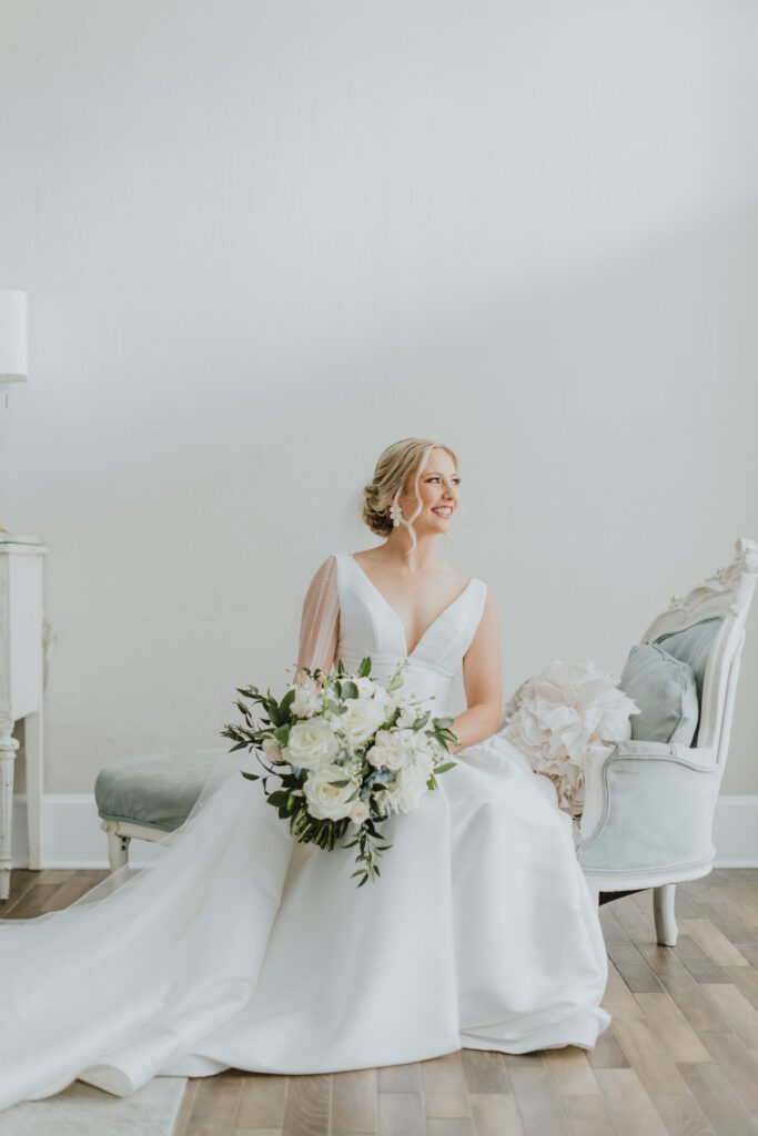 bride on settee for bridal portrait in white room bridal suite