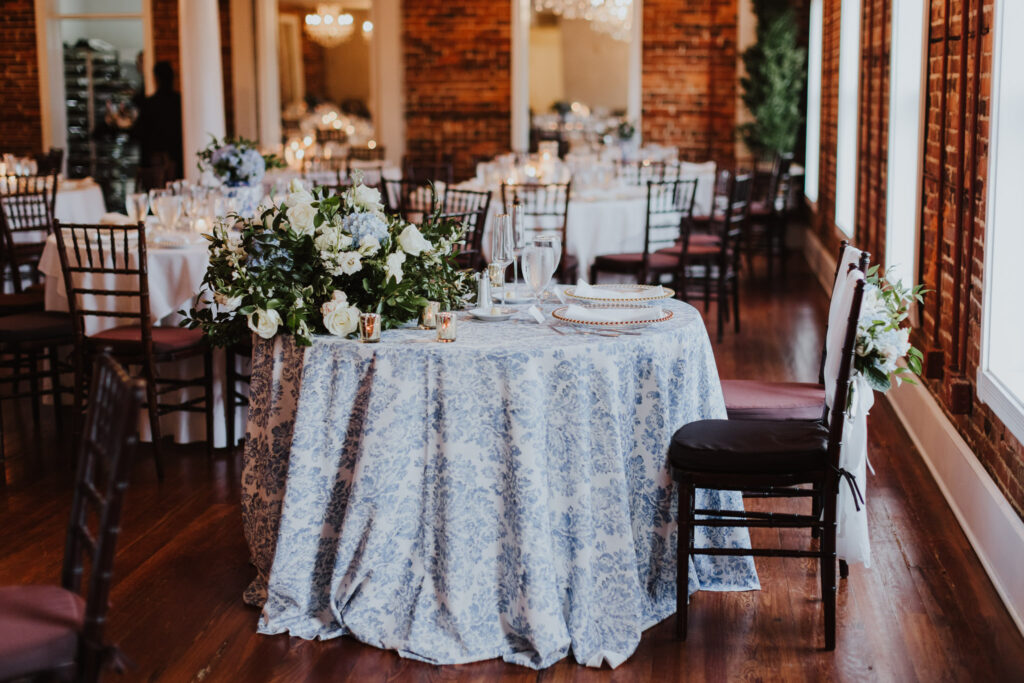 sweetheart table in loft of the white room set up with blue and white linens and large florals