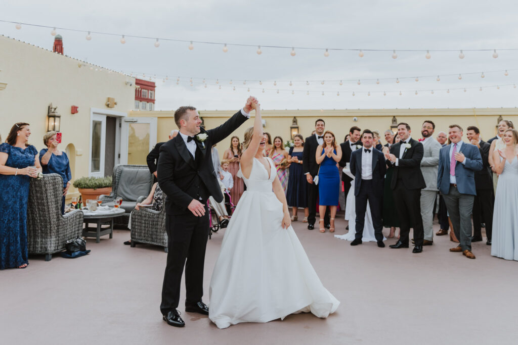 groom spinning bride during first dance on white room rooftop 