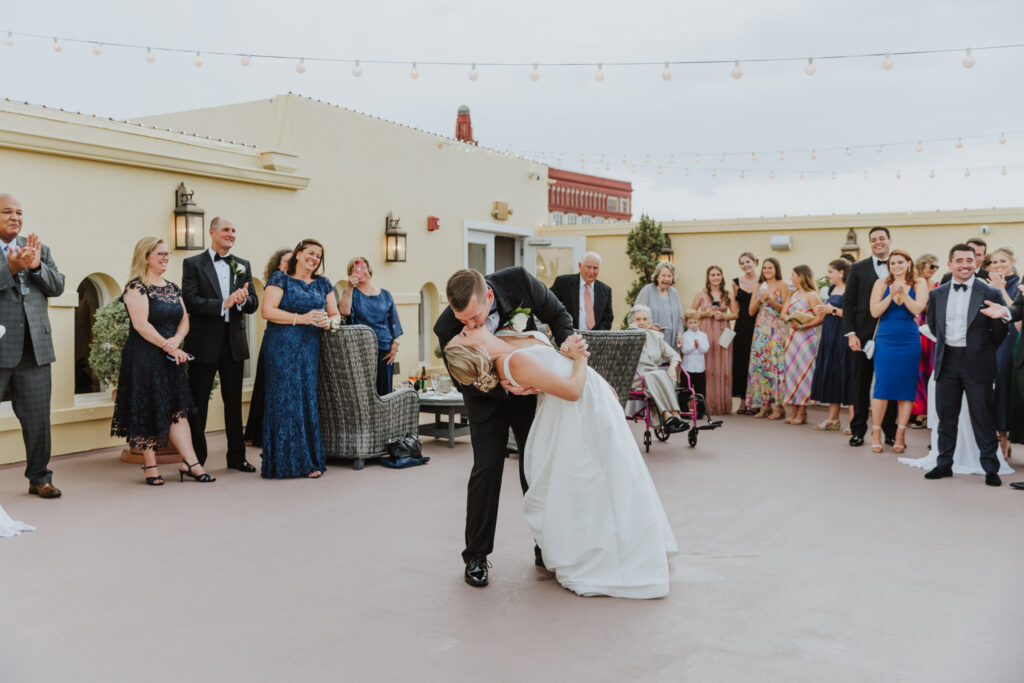 groom dipping bride during first dance on rooftop of white room 