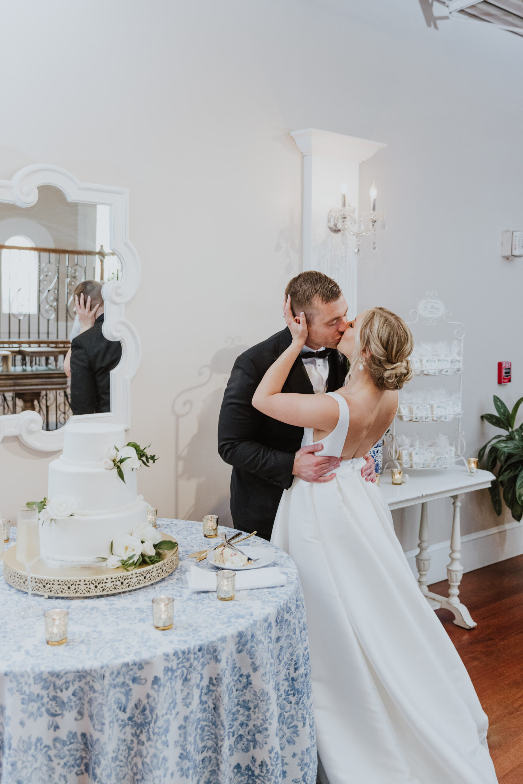 groom and bride kissing after cutting their cake in the white room loft reception space