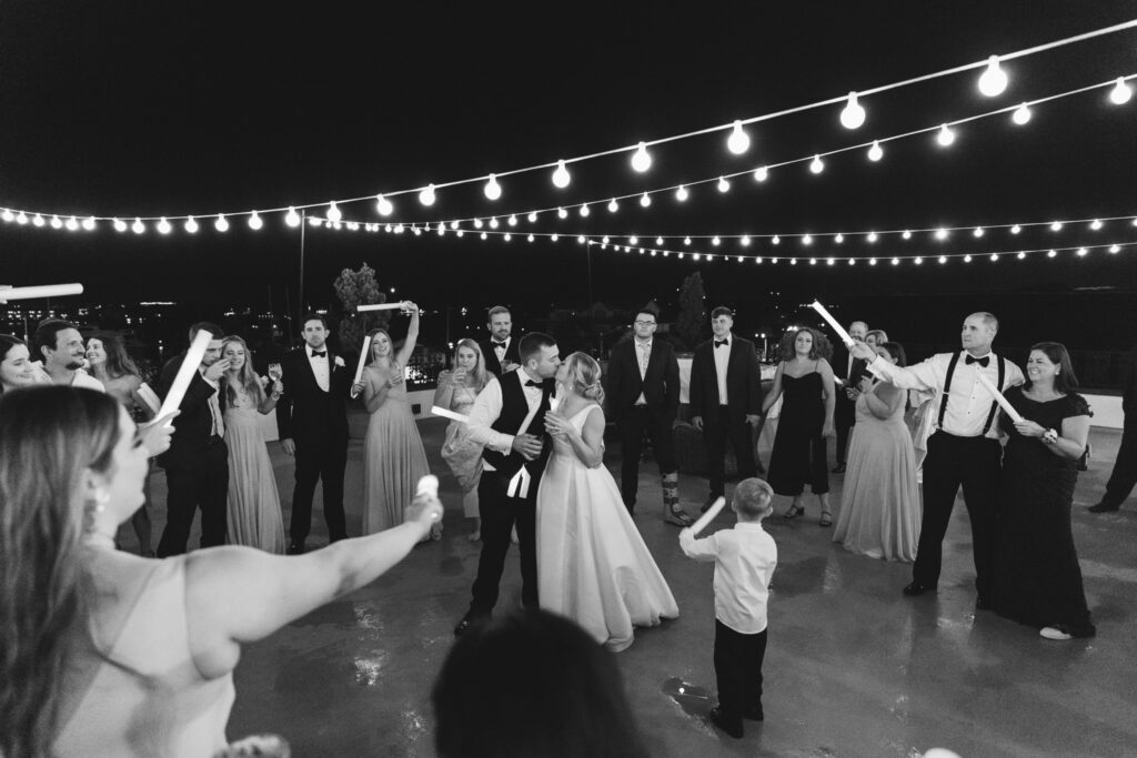 groom and bride kissing in middle of dance floor on reception on rooftop of white room 