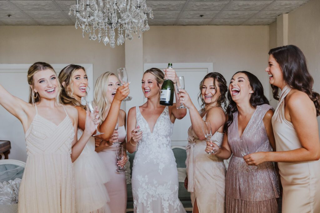 bride and bridesmaids cheers with champagne in the white room bridal suite