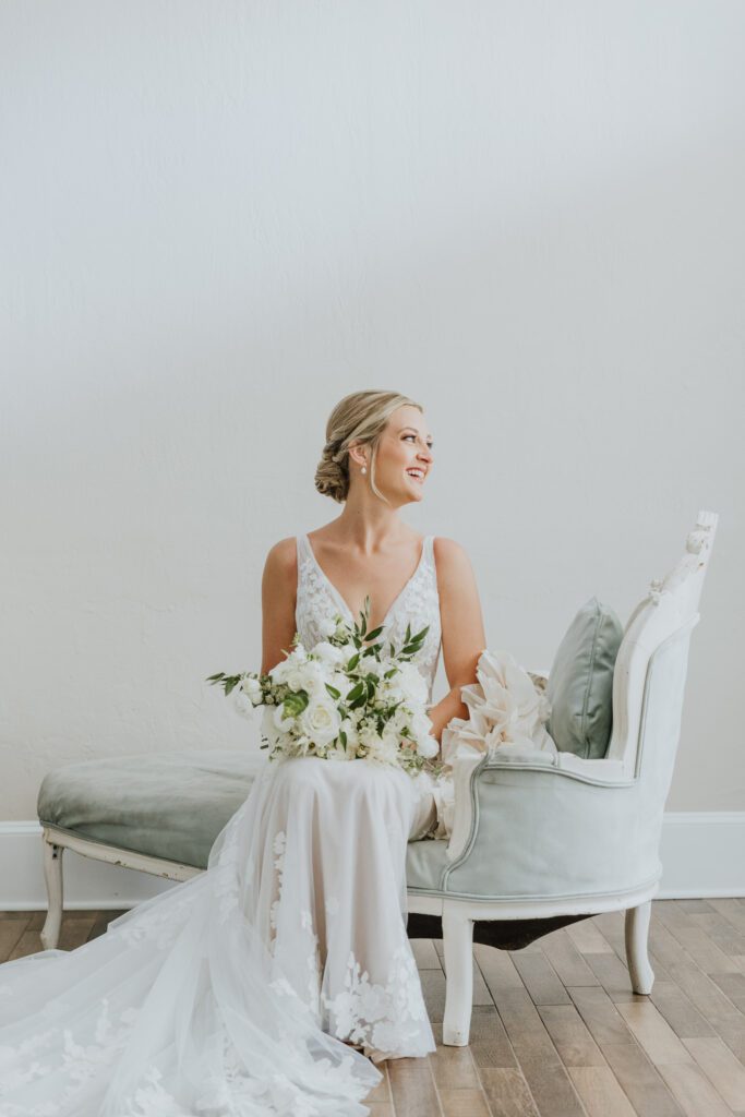 bride sitting on settee in white room bridal suite during bridal portrait on wedding day in st. augustine