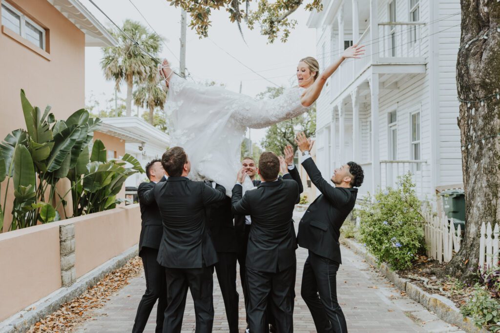 groom and groomsmen throwing bride into the air in the middle of a historic downtown st. augustine street