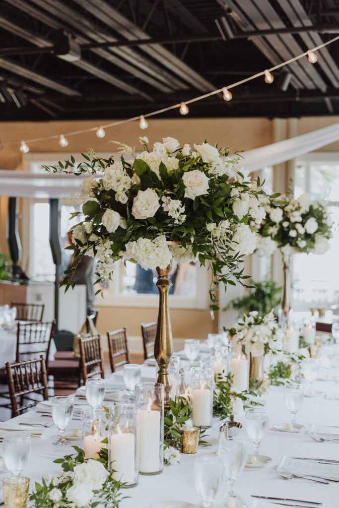 long table wedding reception centerpiece with tall white florals, gold vases and candles