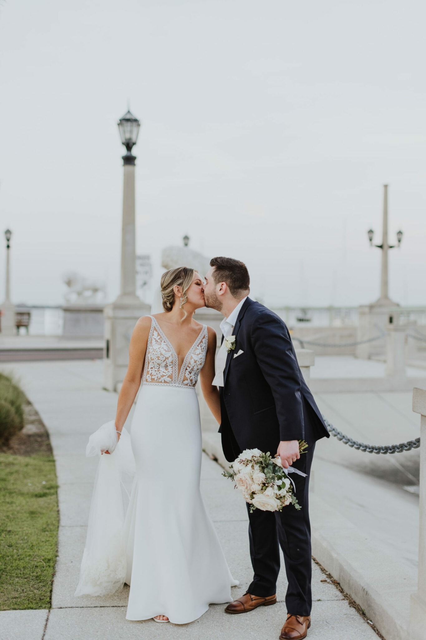 bride and groom kissing while walking along st. augustine bay
