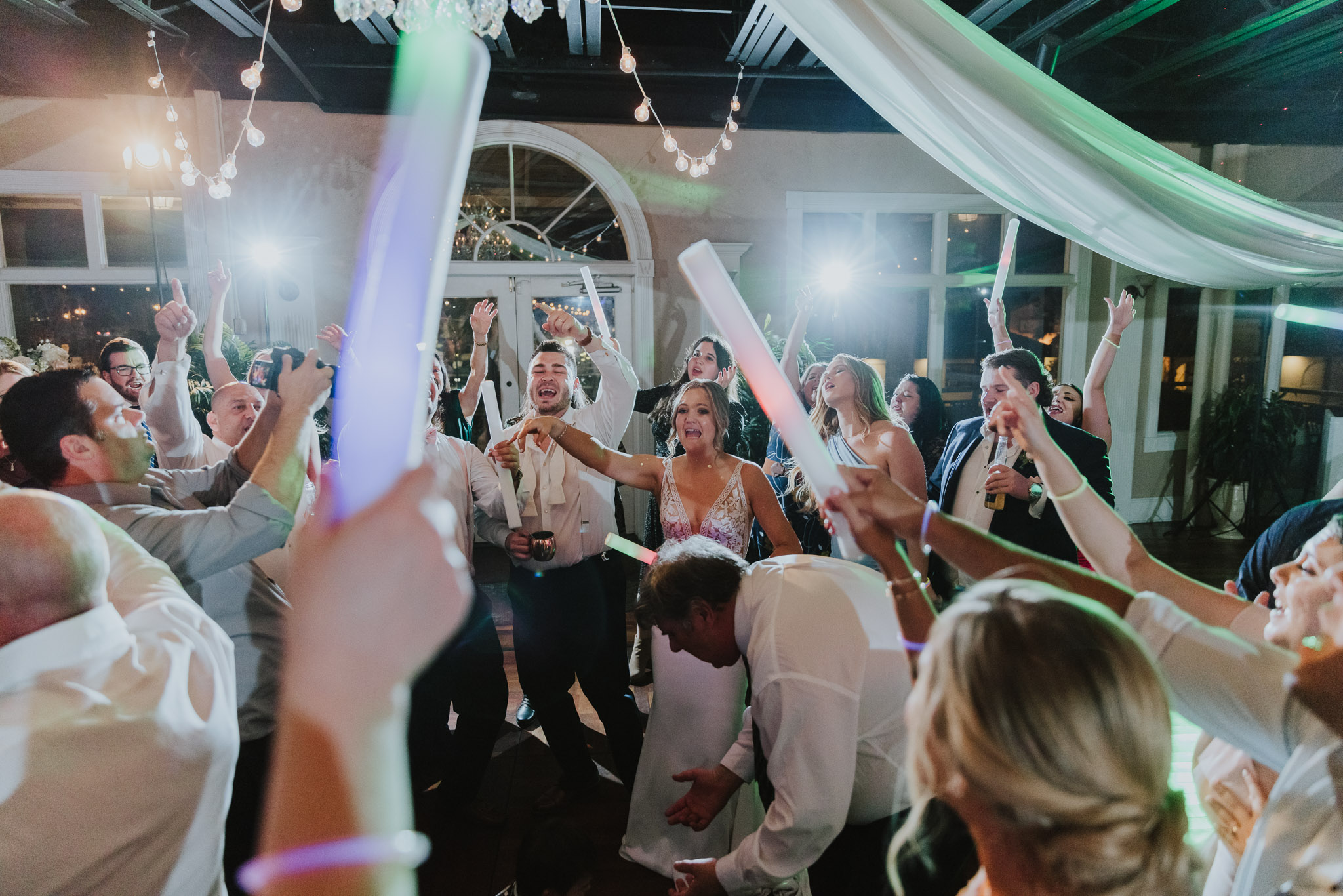 groom and bride dancing with all their guests on the dance floor of the white room 