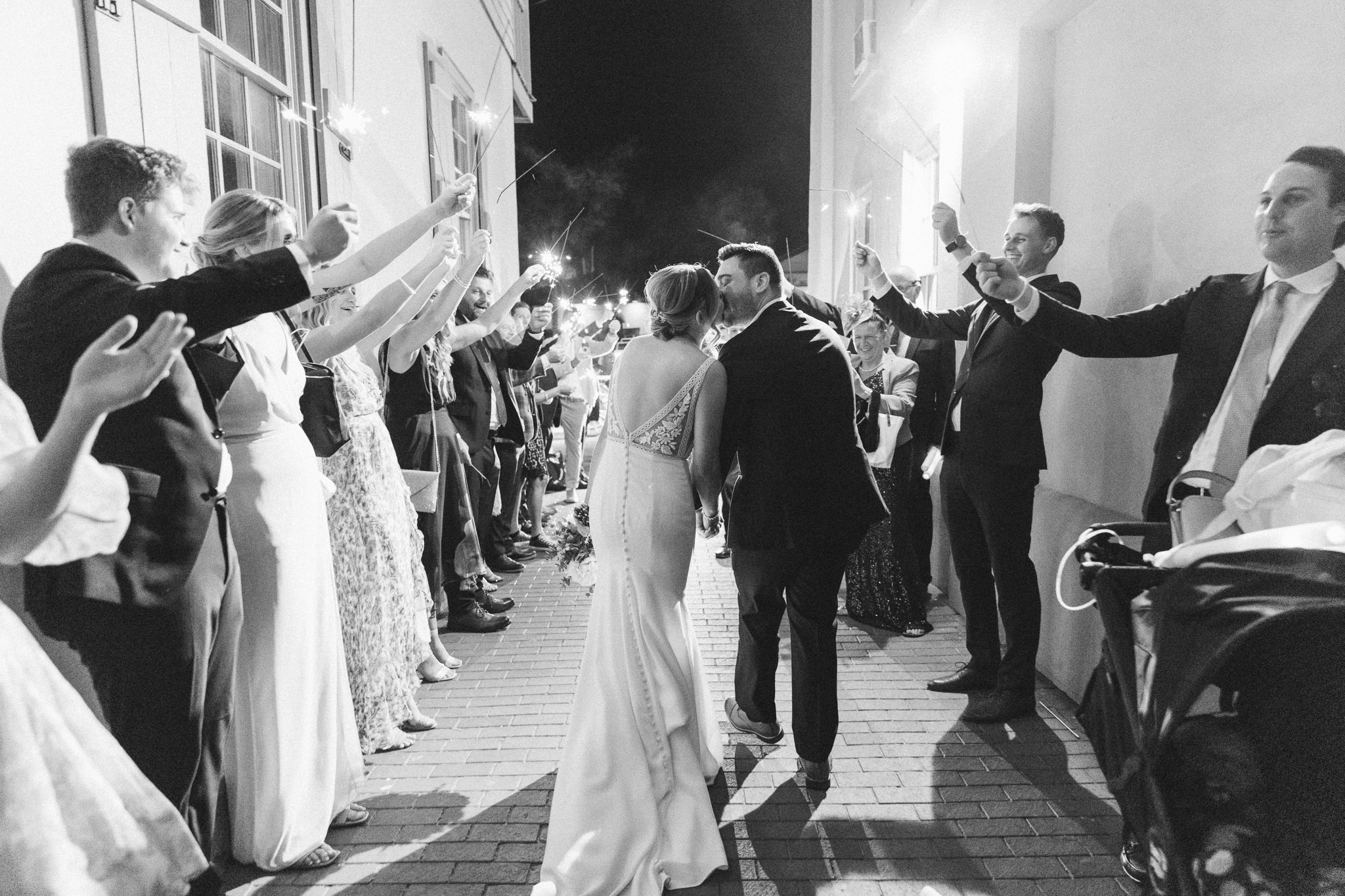 bride and groom leaving their white room wedding reception with a sparkler send off. 